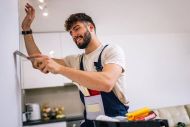 Ressam dairedeki duvarı yumuşatmak için macun bıçağı kullanır. Yüzeyi boyamaya ve profesyonel bir son için hazırlar..