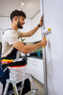 Bir dairedeki ressam, fırçalı duvarlara kireç sürüyor, yeni ve hassas bir iç yenileme üzerinde çalışıyor..