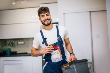 Tamirci bir daireye tam teçhizatlı bir şekilde girer, ev eşyalarını profesyonel aletler ve uzmanlıkla tamir etmeye ve muhafaza etmeye hazırdır..