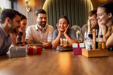 Arkadaşlar bir restoranda doğum gününü kutluyor, doğum günü kızı pastasına mumlar üflerken ve masada hediyelerle şarkı söyleyip alkışlıyorlar..