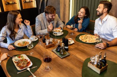 Restoranda pizza, makarna, tavuk, pilav yiyip sohbet ederken şarap içen bir grup iş arkadaşı..