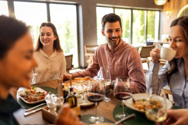 Restoranda pizza, makarna, tavuk, pilav yiyip sohbet ederken şarap içen bir grup iş arkadaşı..