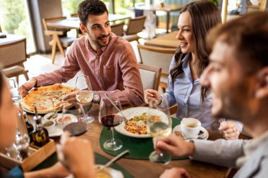 Restoranda pizza, makarna, tavuk, pilav yiyip sohbet ederken şarap içen bir grup iş arkadaşı..
