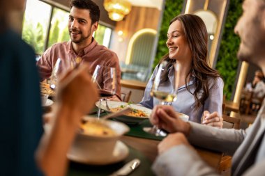 Restoranda pizza, makarna, tavuk, pilav yiyip sohbet ederken şarap içen bir grup iş arkadaşı..