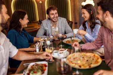 Restoranda pizza, makarna, tavuk, pilav yiyip sohbet ederken şarap içen bir grup iş arkadaşı..