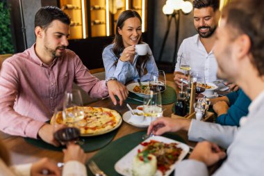 Restoranda pizza, makarna, tavuk, pilav yiyip sohbet ederken şarap içen bir grup iş arkadaşı..