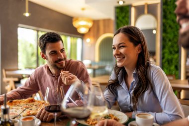 Restoranda pizza, makarna, tavuk, pilav yiyip sohbet ederken şarap içen bir grup iş arkadaşı..