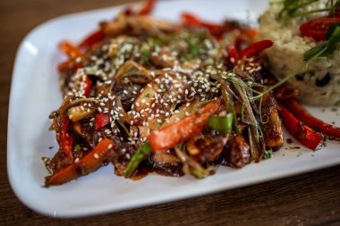 Lezzetli baharatlı tavuk, renkli biber, pirinç ve susam tohumları bir restoranda servis edilir..