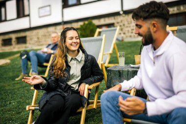 Mutlu genç çift sonbahar boyunca otelin önündeki dinlenme yerlerinde kahve ve meyve suyu içiyor, huzurlu ve romantik bir sonbahar tatili..