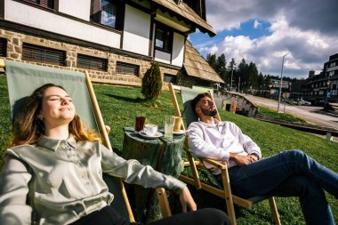 Mutlu genç çift güneşli bir günün tadını çıkarıyor, birlikte dinleniyor ve dışarıda huzurlu bir sonbahar anının tadını çıkarıyor..