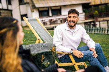 Mutlu genç çift sonbahar boyunca otelin önündeki dinlenme yerlerinde kahve ve meyve suyu içiyor, huzurlu ve romantik bir sonbahar tatili..
