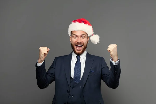 Cheerful businessman in Christmas hat isolated on grey background