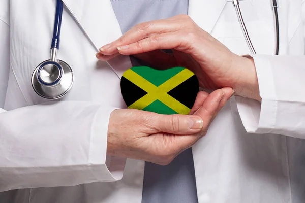 Jamaican doctor holding heart with flag of Jamaica background. Healthcare, charity, insurance and medicine concept