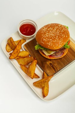 Tahta masada patates kızartması ve ketçap dolu taze gurme burger.