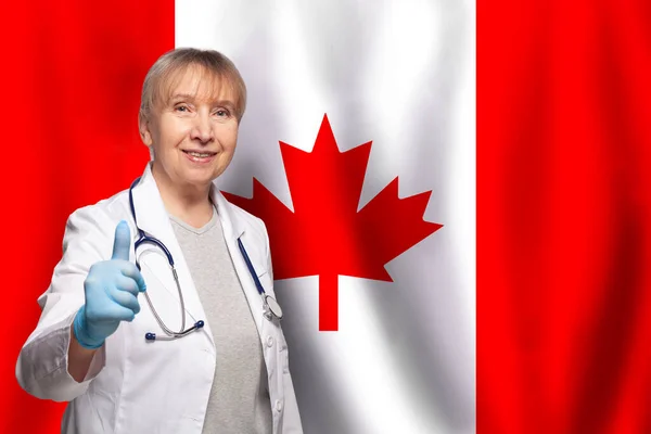 加拿大面带微笑的成熟女医生 手持听诊器 手持加拿大国旗背景 — 图库照片