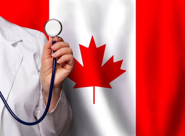加拿大医务工作者的手 带听诊器 悬挂加拿大国旗背景 — 图库照片