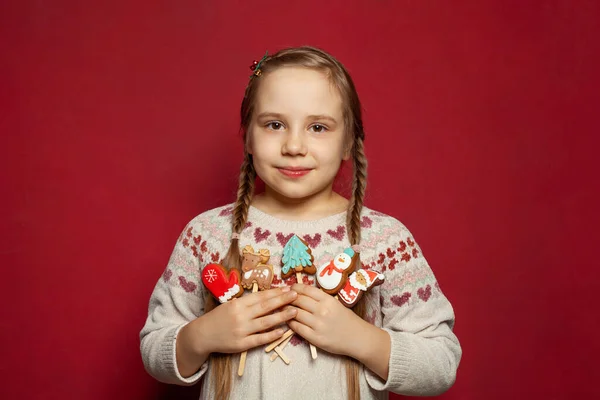 Junge Weihnachtsmädchen Tragen Gestrickten Weihnachtspullover Mit Weihnachtsplätzchen Auf Rotem Hintergrund — Stockfoto