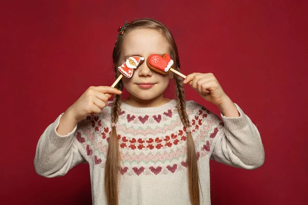 Маленькая Девочка Улыбается Прячет Глаза Пряниками Санта Клауса Фоне Красного — стоковое фото