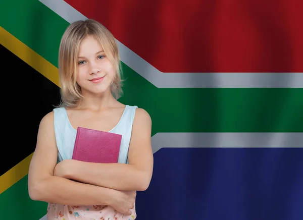 带着一本关于南非国旗背景的书的快乐的未成年女学生 — 图库照片