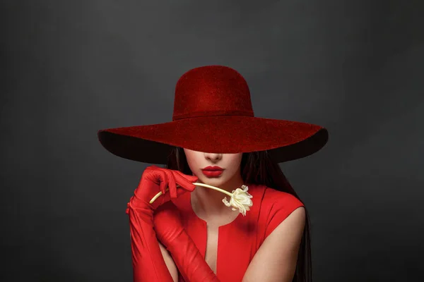 一个穿着红色衣服 头戴红色宽边帽 头戴黑色红宽边帽的年轻漂亮女人的画像 图库图片