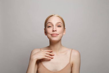 Taze tenli, çıplak omuzlu, açık arkaplanda güzel bir genç kadın.