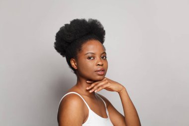 Güzel, genç, esmer, temiz tenli bir kadın yüzüne dokunuyor. Yüz bakımı, kozmetoloji, güzellik ve cilt bakımı konsepti