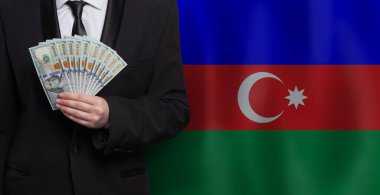 Azerbaycan bayrağına karşı 100 dolarlık banknotlar gösteren adam