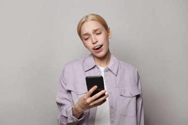 Akıllı telefon kullanan ve beyaz arka plan üzerinden mesaj gönderen genç, şaşkın bir kadın. 