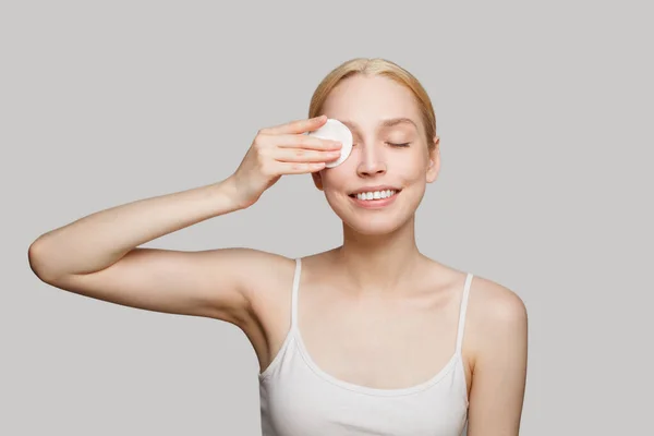 stock image Young attractive smiling woman removing make up on white background