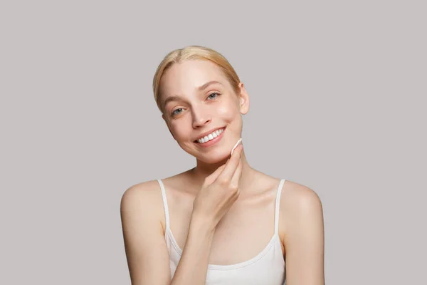一个快乐的年轻女人 在白皙的背景下 去除脸上的化妆品和新鲜洁白的面部肌肤 图库照片
