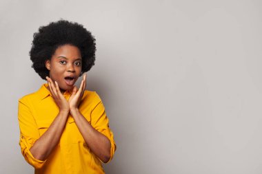 Mutlu bir gülümseme, beyaz stüdyo duvarına yaslanmış sarı gömlekli esmer bir kadını şaşırttı.