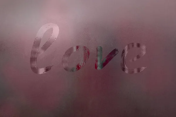 Inscription on misted window: love, abstract red background