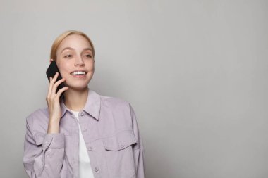 Young attractive blonde woman in casual clothes talking on phone against white studio wall banner background