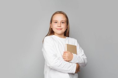 Funny smiling child school girl with books against white studio wall banner background