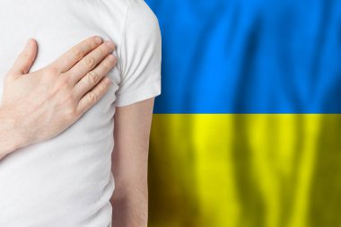 Ukrainian person with hand on heart on the background of Ukraine flag. Patriotism, country, national, pride concept