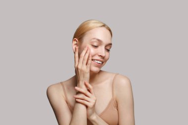 Beautiful woman spa model touching her fresh skin her hand on white background. Facial treatment, cosmetology, skincare, hydration, hygiene and beauty concept