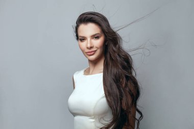 Gri arka planda sağlıklı dalgalı saçları olan güzel bir kadının portresi.