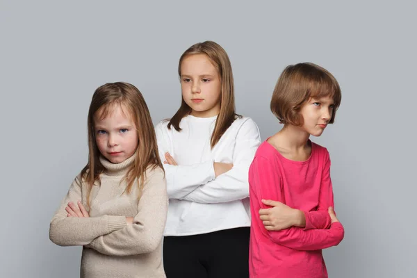 Three upset kids friends standing with crossed arms. Young girls 8-10 years old