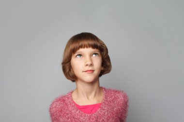 Pretty child girl looking up on grey background