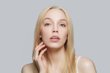 Gorgeous woman with blonde hair and hand isolated on grey background. Beauty, cosmetics, skincare, glamour