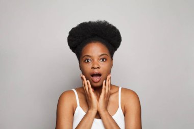 Screaming young brunette woman standing on grey studio wall background