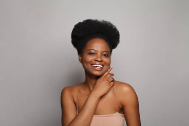 Happy lady. Beautiful young model woman with healthy clean skin smiling on grey background