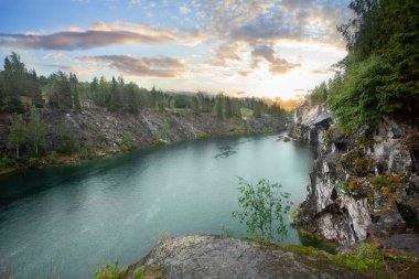Sunny landscape of orange sunrise, forest and bright blue mountain river