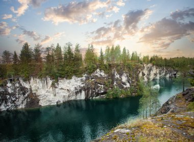 Bulutlu günbatımının güzel manzarası, yeşil orman ve soğuk mavi dağ nehri.