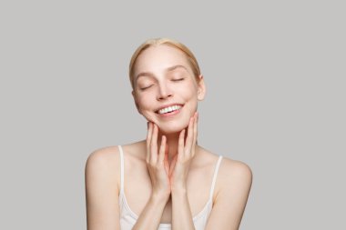 Güzel bir kadının portresi ve elleri gri arka planda izole. Güzellik, kozmetik, cilt bakımı, cazibe.