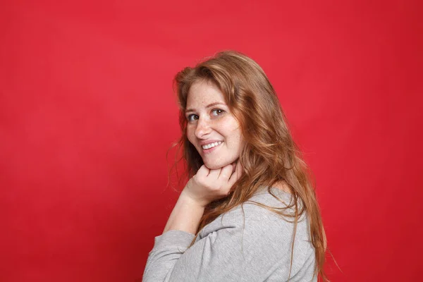 Gelukkig Glimlachen Brunette Vrouw Grijs Trui Staan Zijwaarts Rode Studio — Stockfoto