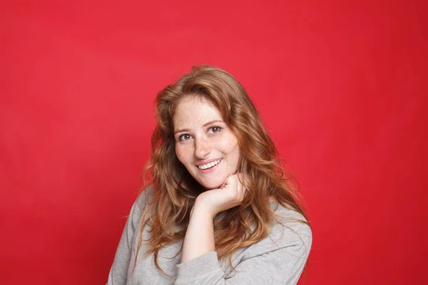 幸せな笑顔ブルネット女性でグレーセーターオン赤スタジオ壁の背景 — ストック写真