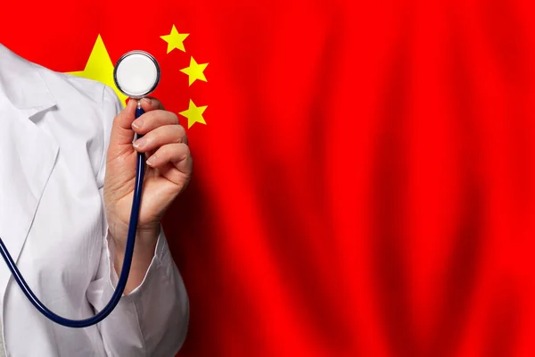 Chinese doctor\'s hand with stethoscope on the background of flag of China Medicine, clinic, practitioner, healthcare