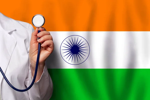 Indian doctor\'s hand with stethoscope on the background of flag of India Medicine, clinic, practitioner, healthcare
