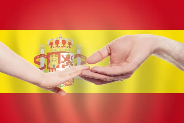 以西班牙国旗为背景的西班牙婴儿和父母的手帮助 慈善概念 — 图库照片